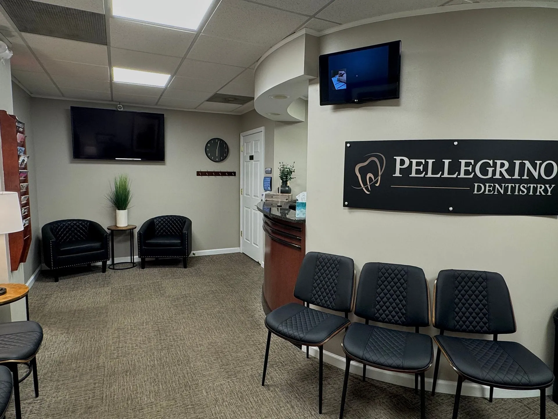 Pellegrino Dentistry waiting room with comfortable seating, wall signage, and TV displays.
