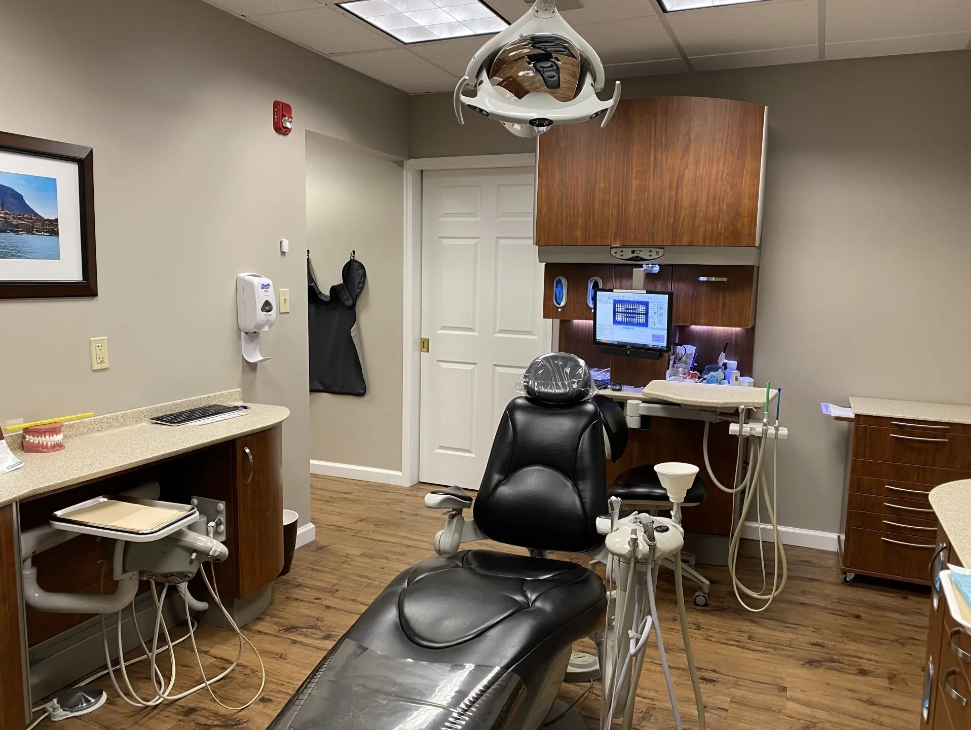 Modern dental operatory with patient chair, overhead light, and treatment equipment in clinical setting.