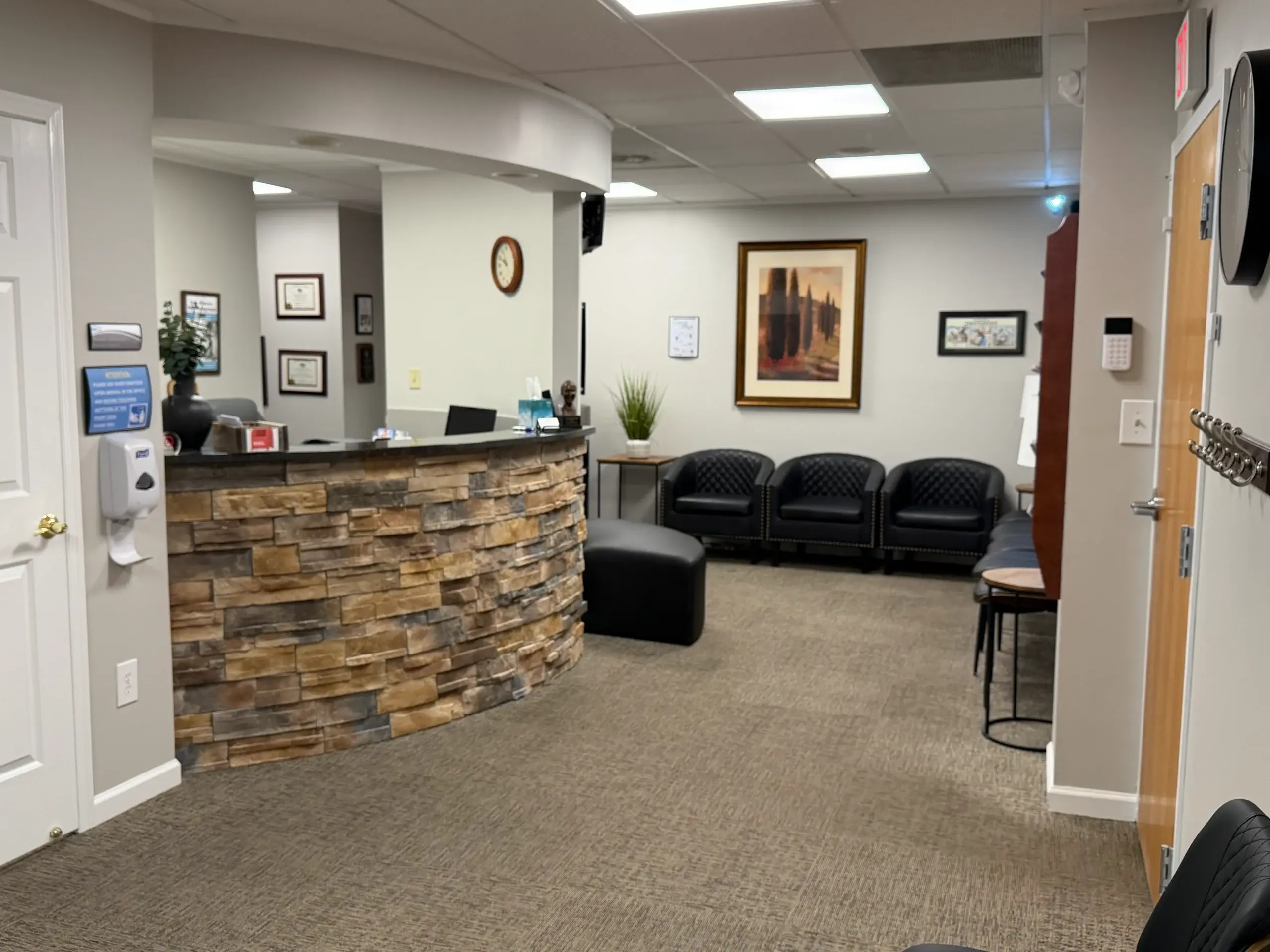 Pellegrino Family Dental waiting room with stone reception desk, black leather seating, and calming decor in Allentown, PA.